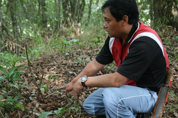 Seediq man displays trap in forest
